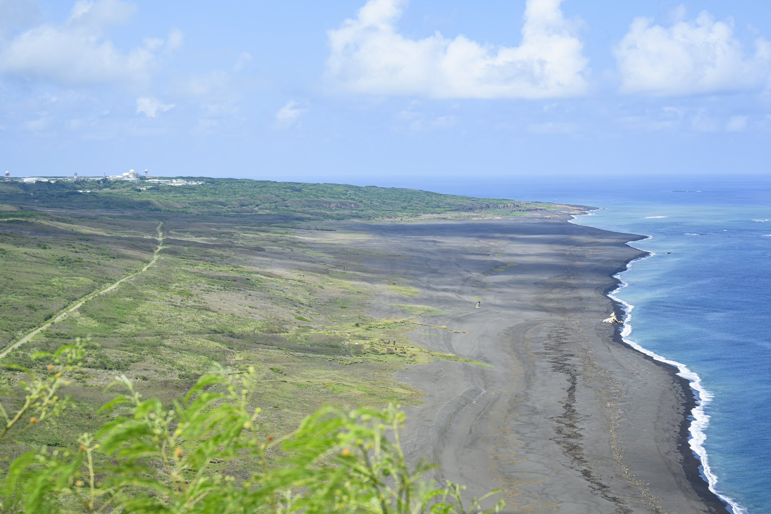 山頂から望む島の全景と黒い砂浜